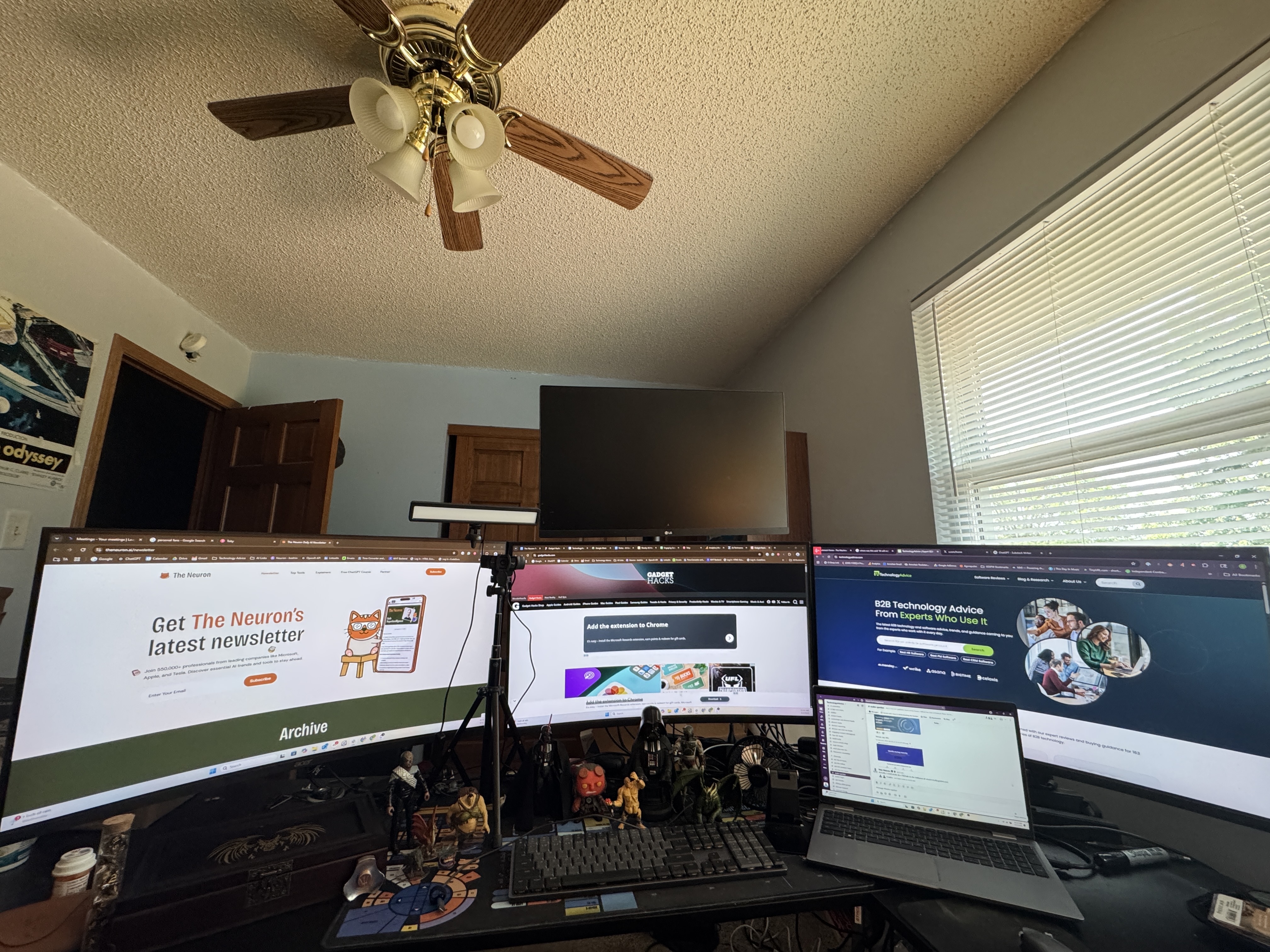 The source photograph: a desk with three wide monitors, a fourth above, laptop, figurines, a brass ceiling fan, wooden doors, and window blinds.